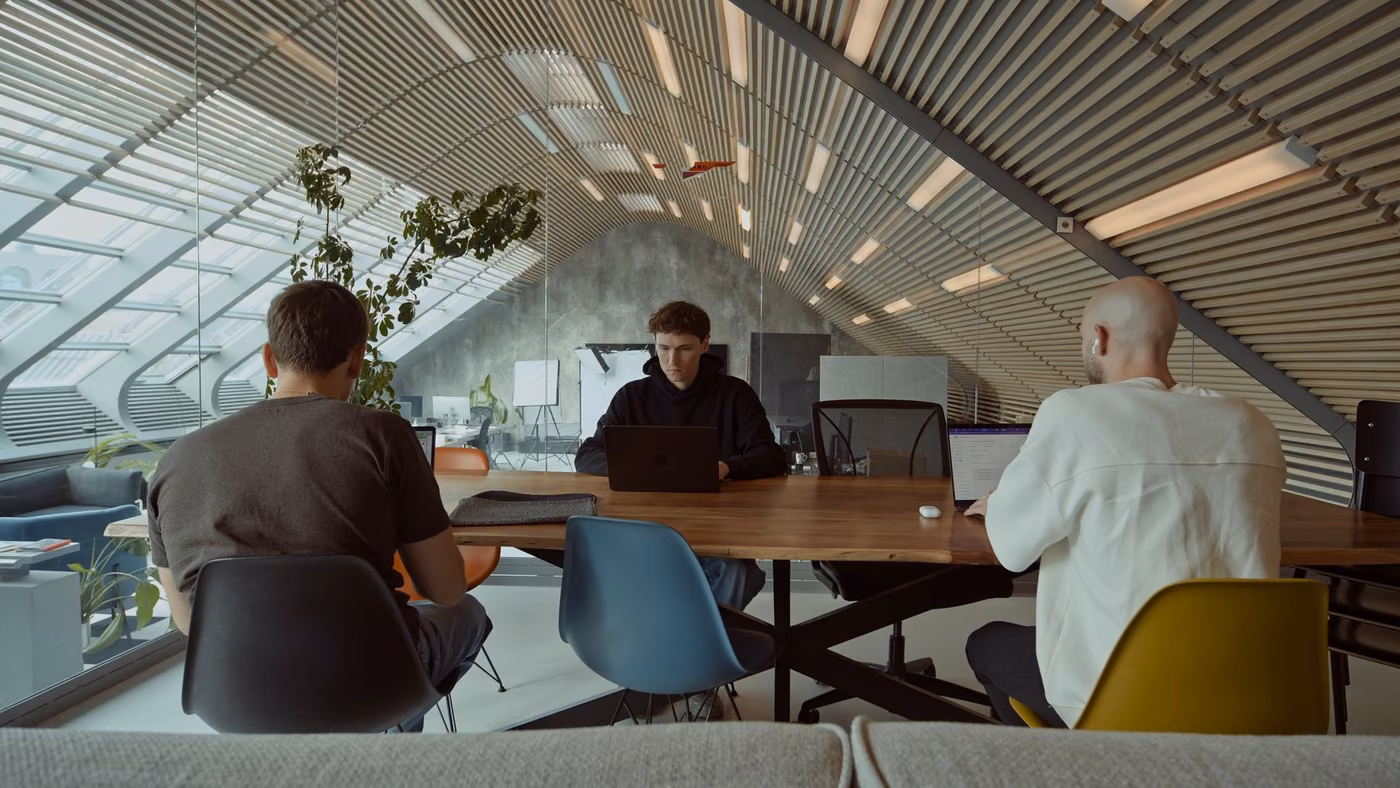 Three Jamie team members working at a shared table in the office